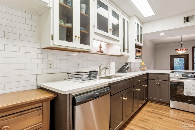 kitchen with a sink, visible vents, backsplash, and stainless steel appliances