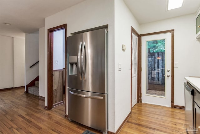 kitchen featuring light countertops, light wood-type flooring, baseboards, and appliances with stainless steel finishes