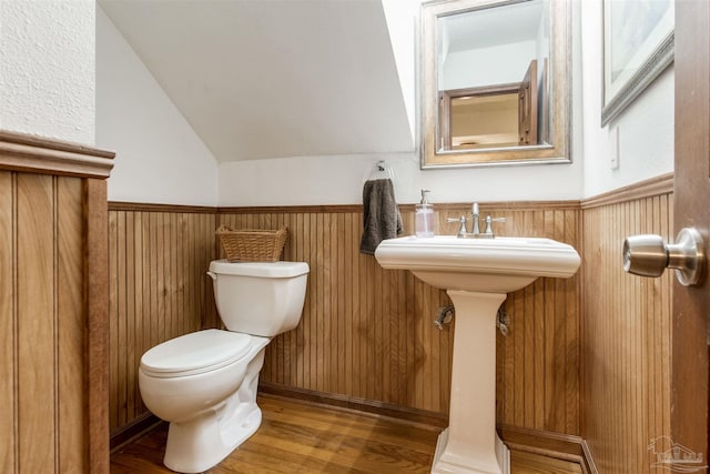 bathroom with lofted ceiling, a wainscoted wall, toilet, and wood finished floors