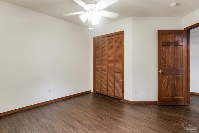 unfurnished bedroom featuring dark wood-style flooring, a closet, baseboards, and a ceiling fan