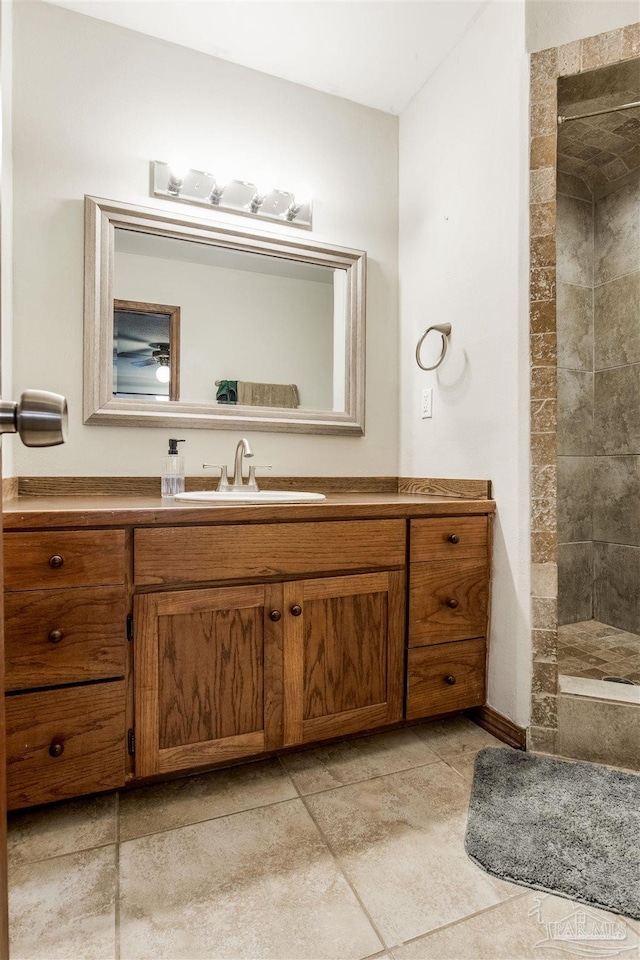 full bath featuring a tile shower, vanity, and tile patterned flooring