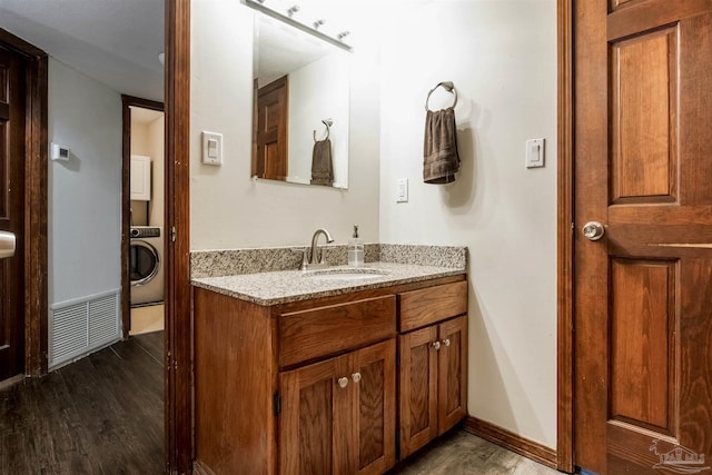 bathroom with visible vents, washer / dryer, vanity, and wood finished floors