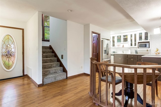 dining space with visible vents, baseboards, light wood-style floors, and stairs