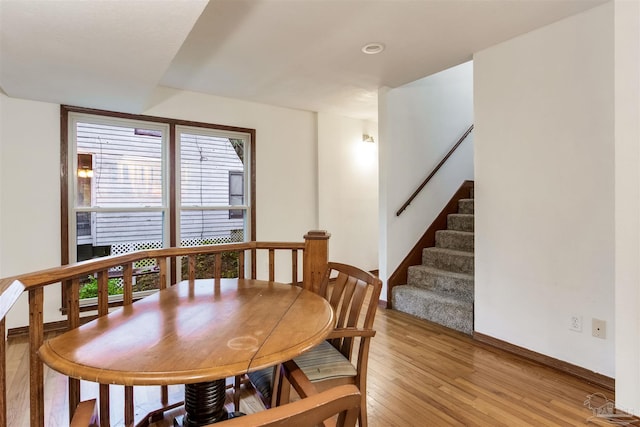 dining area featuring baseboards, light wood-type flooring, and stairs