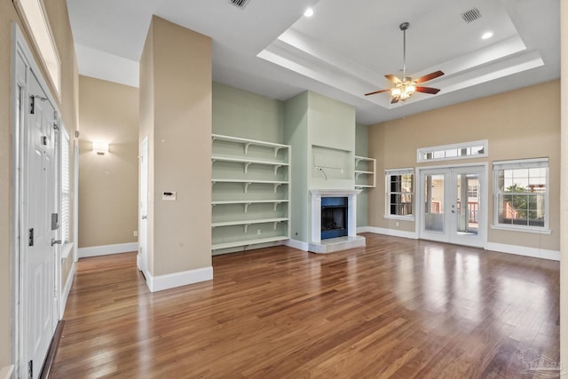 unfurnished living room featuring hardwood / wood-style floors, a tray ceiling, and ceiling fan