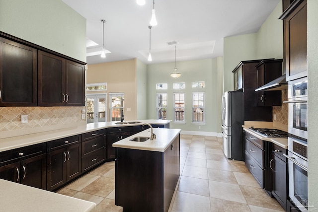 kitchen featuring backsplash, decorative light fixtures, stainless steel appliances, and a kitchen island with sink