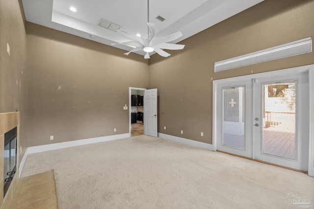 unfurnished living room featuring a multi sided fireplace, ceiling fan, a towering ceiling, and light colored carpet