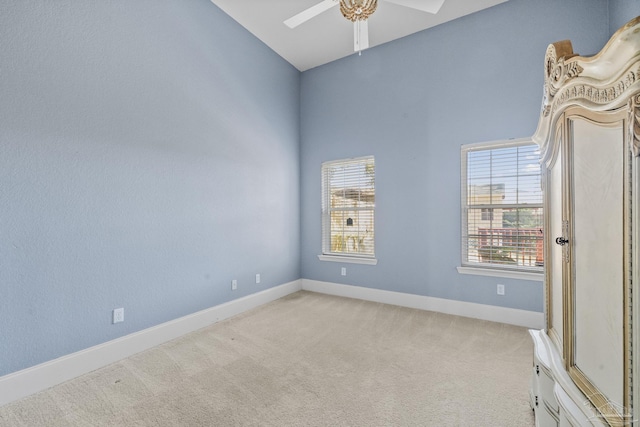 carpeted spare room featuring ceiling fan and lofted ceiling