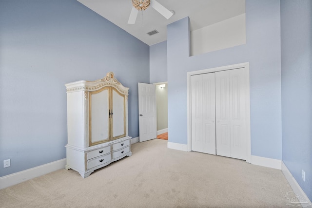 unfurnished bedroom featuring light carpet, a closet, high vaulted ceiling, and ceiling fan