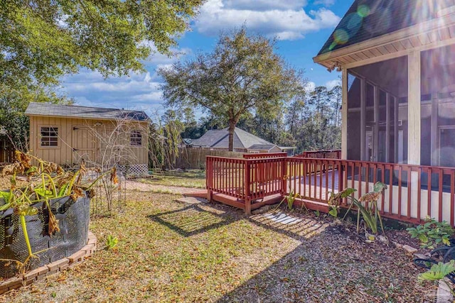 view of yard featuring a sunroom, a shed, and a wooden deck