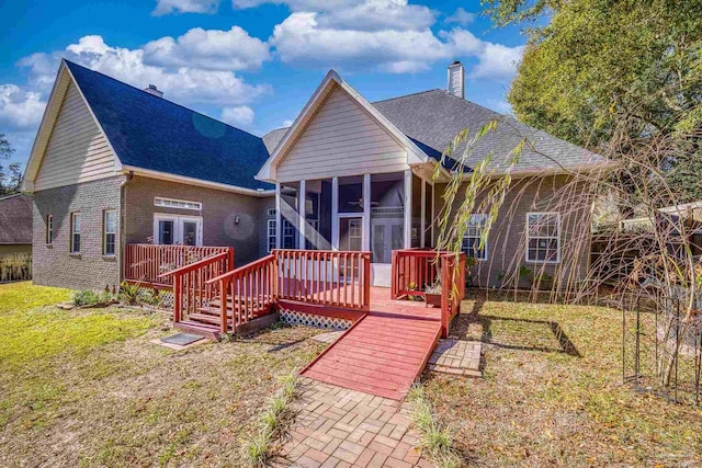 bungalow-style house featuring french doors, a front lawn, a wooden deck, and a sunroom