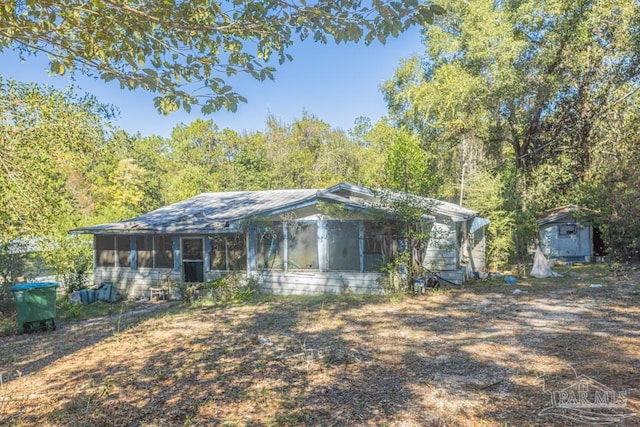 view of front of house featuring a sunroom and a storage unit