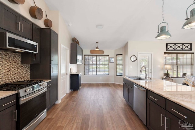 420 Palm Lake Dr, Pensacola, FL 32507 - kitchen with stainless steel appliances, a sink, light wood-type flooring, decorative backsplash, and hanging light fixtures
