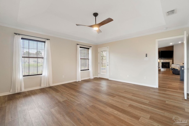 420 Palm Lake Dr, Pensacola, FL 32507 - unfurnished room with a ceiling fan, a fireplace, light wood-type flooring, ornamental molding, and a tray ceiling