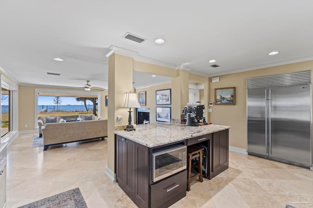 kitchen with crown molding, visible vents, open floor plan, dark brown cabinetry, and built in refrigerator