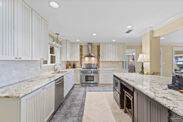 kitchen with recessed lighting, stainless steel appliances, a sink, visible vents, and wall chimney exhaust hood