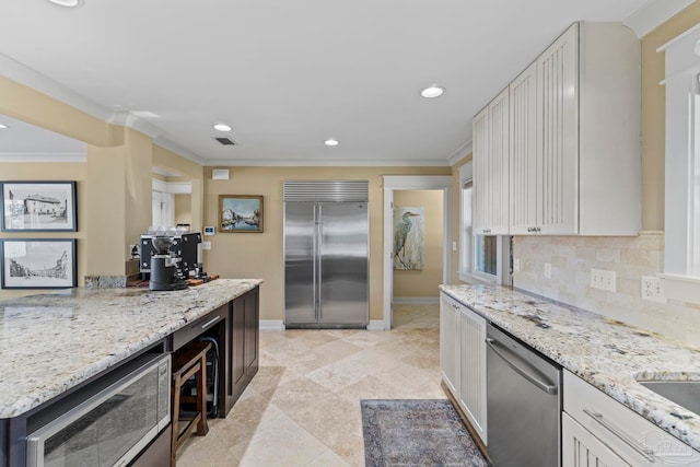 kitchen with stainless steel appliances, ornamental molding, light stone counters, and tasteful backsplash