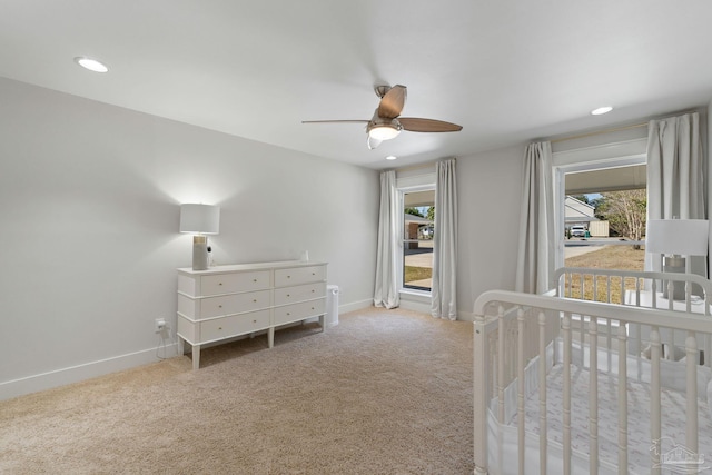 bedroom featuring carpet floors, a crib, multiple windows, and baseboards