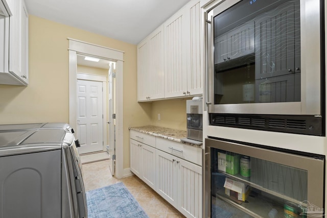 kitchen with washer and dryer, white cabinetry, and light tile patterned floors