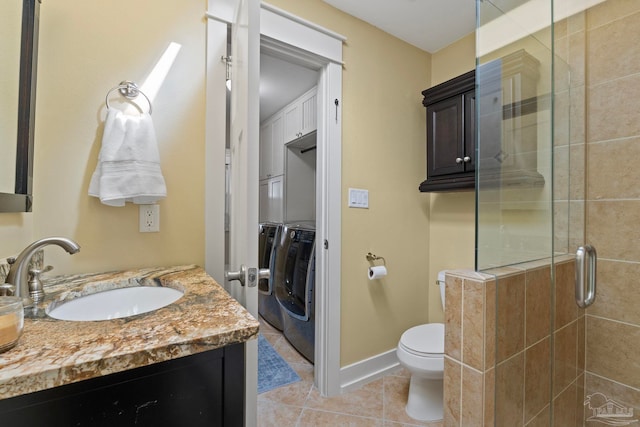 bathroom with a stall shower, baseboards, toilet, tile patterned flooring, and separate washer and dryer