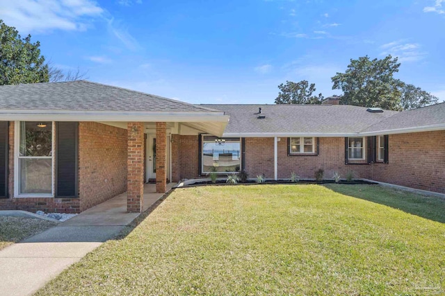 single story home with brick siding, a chimney, a front lawn, and roof with shingles