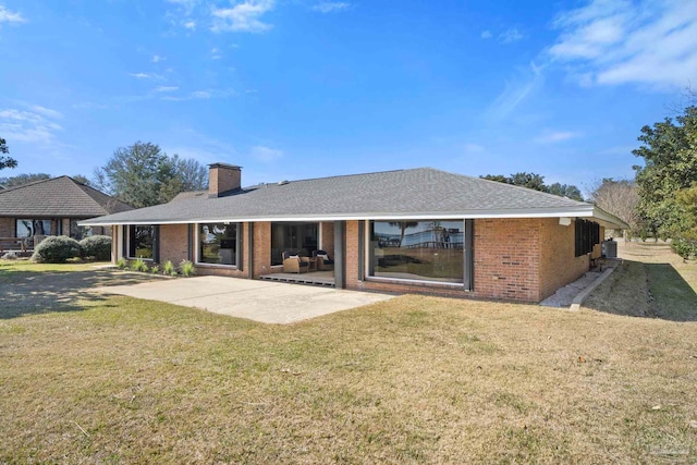 back of property featuring brick siding, a yard, a chimney, central AC unit, and a patio area