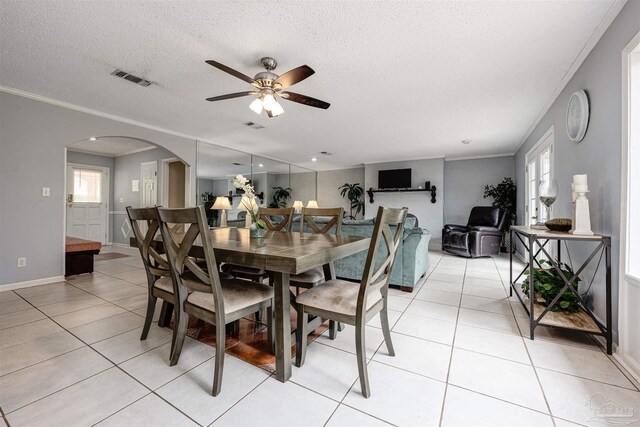 tiled dining space featuring ceiling fan, a textured ceiling, and ornamental molding