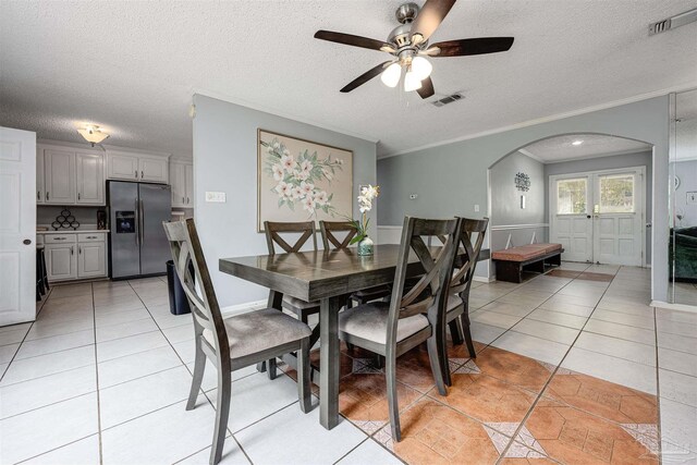 tiled dining space with a textured ceiling, ceiling fan, and crown molding