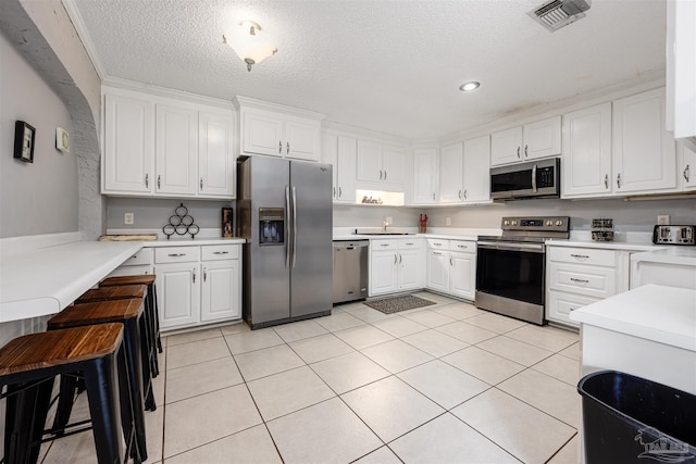 kitchen with white cabinetry, sink, appliances with stainless steel finishes, a textured ceiling, and light tile patterned floors