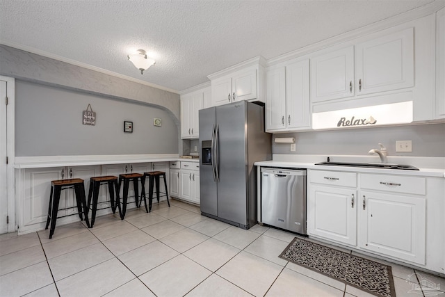 kitchen with white cabinets, stainless steel appliances, light tile patterned flooring, and a breakfast bar area