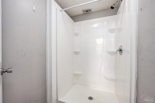 bathroom with a shower and a textured ceiling