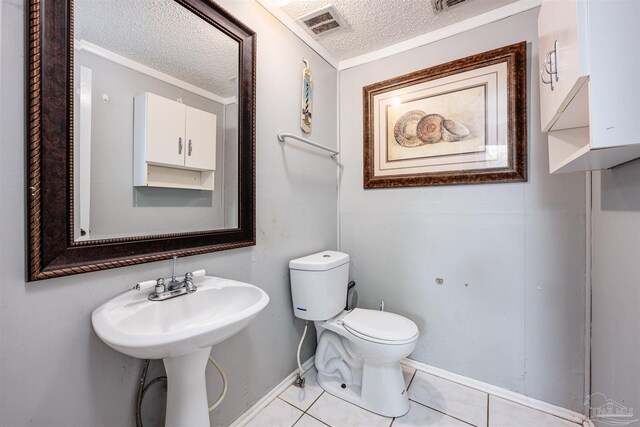 bathroom with a textured ceiling, toilet, and tile patterned flooring