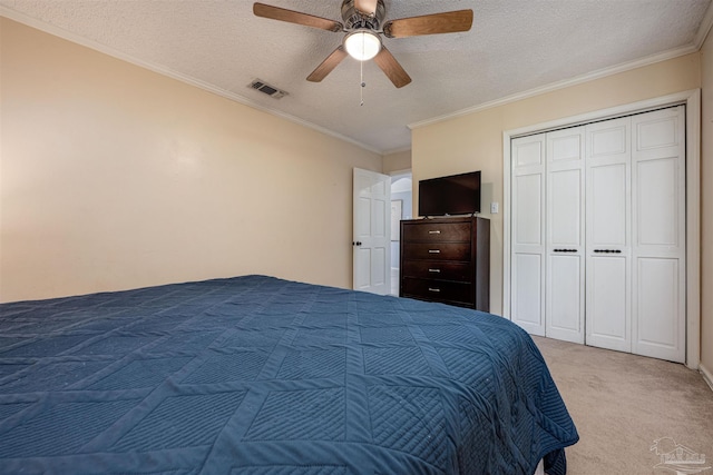 carpeted bedroom with crown molding, a textured ceiling, ceiling fan, and a closet