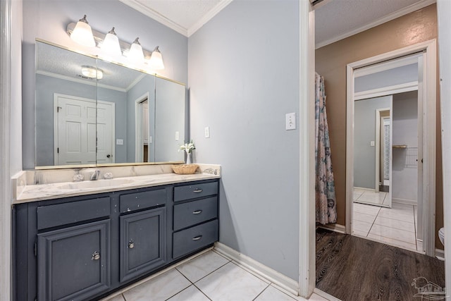 bathroom featuring hardwood / wood-style flooring, a textured ceiling, vanity, and ornamental molding