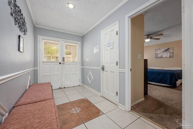 foyer entrance with a textured ceiling, light tile patterned floors, crown molding, and ceiling fan