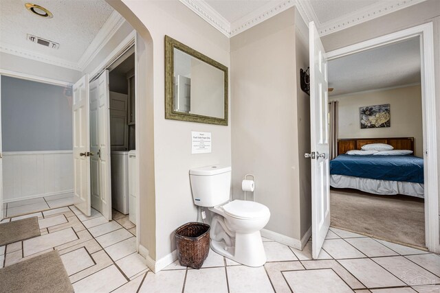 bathroom featuring crown molding, tile patterned flooring, toilet, and a textured ceiling