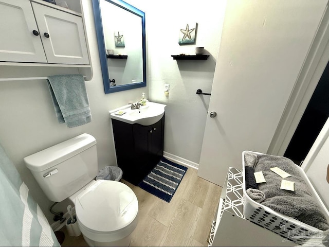 bathroom with baseboards, vanity, toilet, and wood finished floors