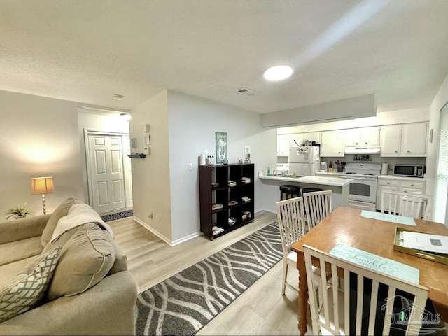 living area featuring a toaster, light wood-style floors, baseboards, and visible vents