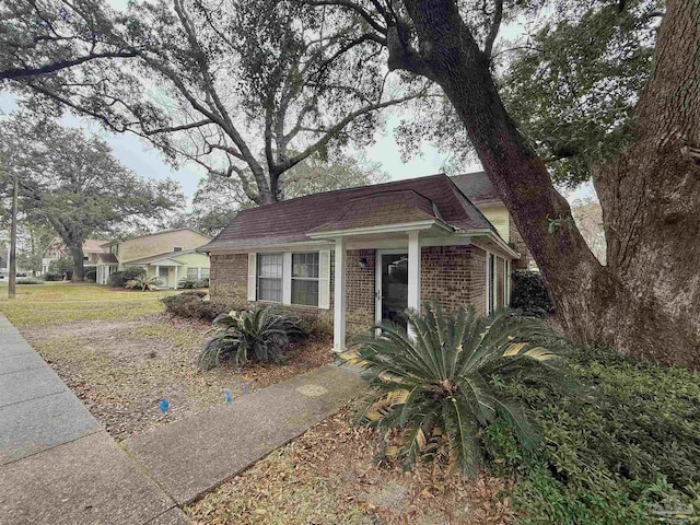 view of front of home with brick siding and roof with shingles