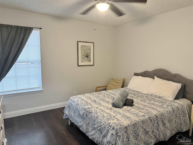 bedroom with a ceiling fan, a textured ceiling, baseboards, and dark wood-type flooring