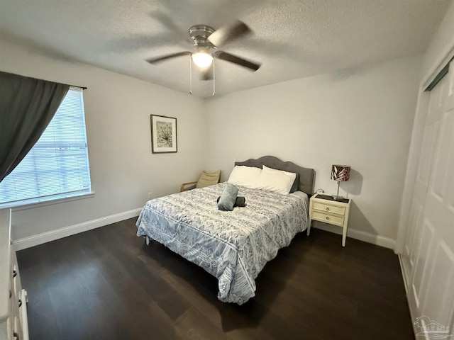 bedroom with dark wood-type flooring, a textured ceiling, and baseboards