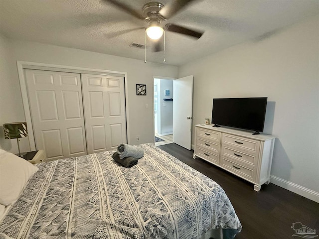 bedroom with a textured ceiling, ceiling fan, visible vents, a closet, and dark wood finished floors