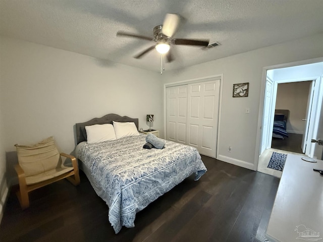 bedroom featuring baseboards, visible vents, dark wood-style flooring, a textured ceiling, and a closet