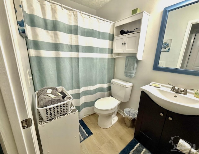 full bath featuring curtained shower, toilet, a textured ceiling, vanity, and wood finished floors