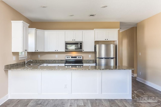 kitchen featuring visible vents, white cabinets, appliances with stainless steel finishes, wood finished floors, and stone counters