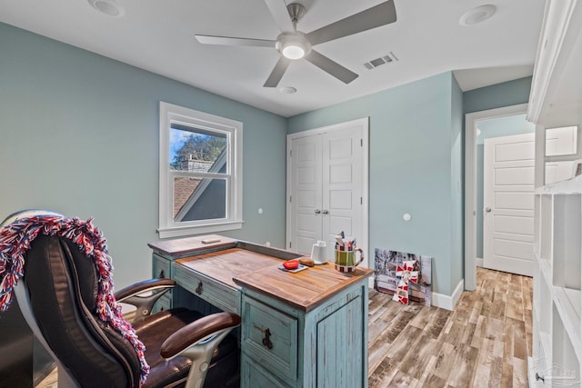 office with light wood-type flooring and ceiling fan