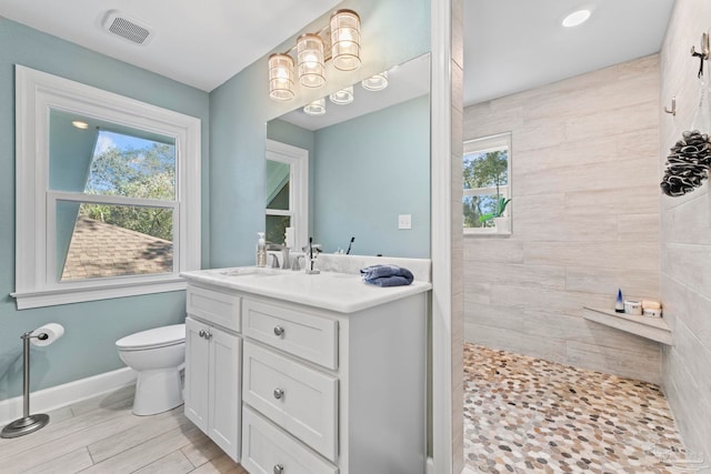 bathroom featuring toilet, vanity, and tiled shower