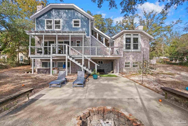 rear view of house featuring a patio area, a pergola, a wooden deck, and a fire pit