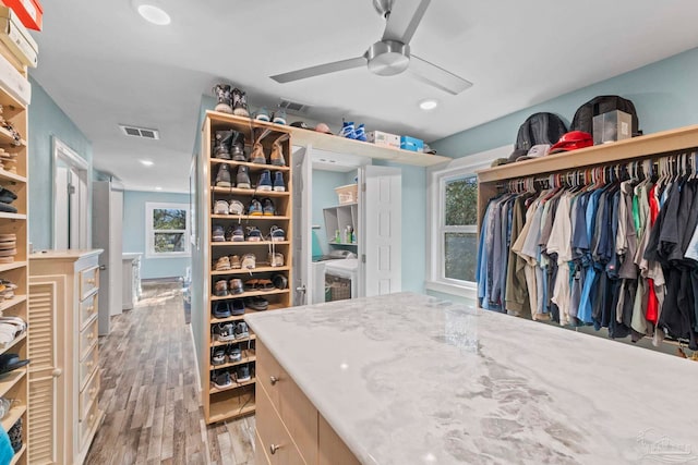 walk in closet with ceiling fan and light hardwood / wood-style flooring