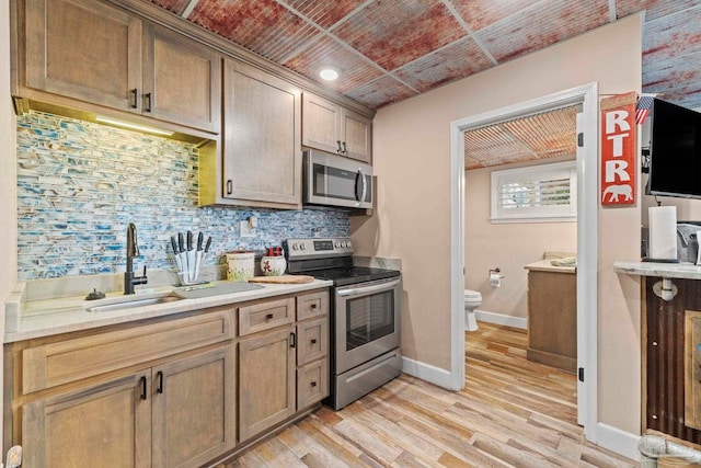 kitchen featuring sink, stainless steel appliances, light hardwood / wood-style floors, and decorative backsplash